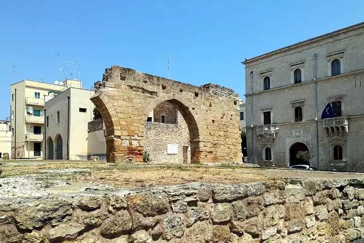La facciata di Palazzo Granafei-Nervegna e l'arco di epoca romana sulla piazza antistante.